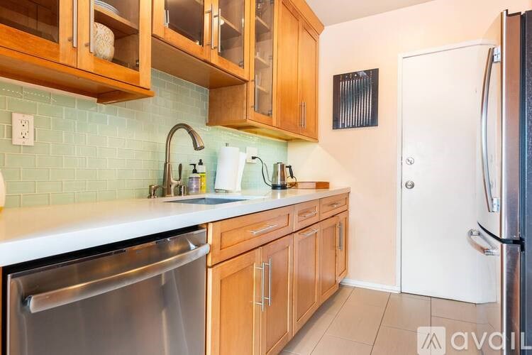 A kitchen with wooden cabinets and a stainless steel dishwasher.