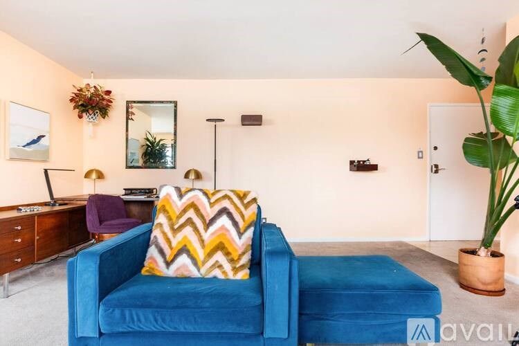 A blue couch with a yellow and orange pillow is in the center of a living room.