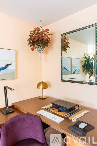 A purple chair sits in front of a desk with a laptop, a phone, and a lamp.