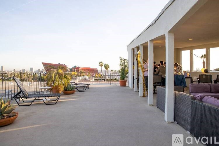 A patio area with a white building, some chairs and a table with people sitting at it.