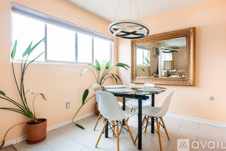 A dining room with a round table and chairs, a mirror, and a potted plant.