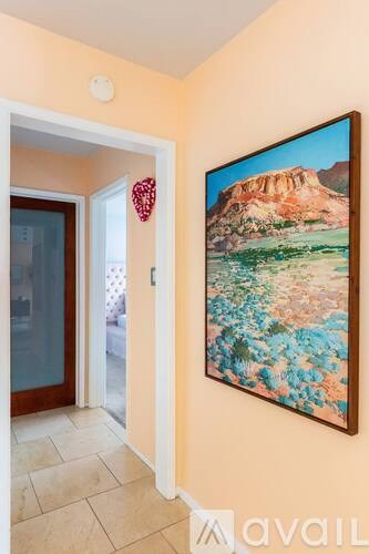 A painting of a desert landscape hangs on a wall in a room.