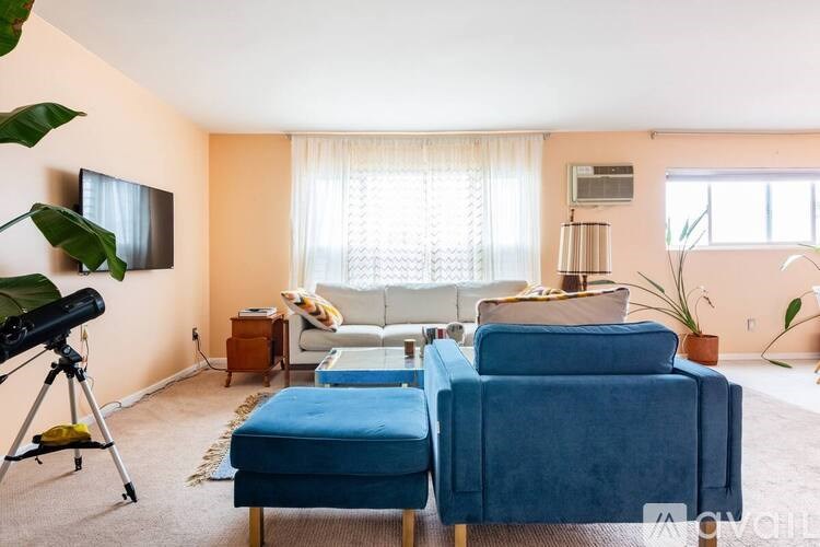 A living room with a blue couch and a television on the wall.