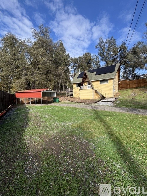 A grassy area with a house and a shed in the background.