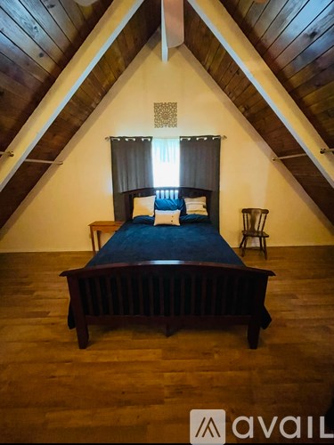 A bed with a wooden headboard and footboard sits in a room with wooden floors and a wooden ceiling.