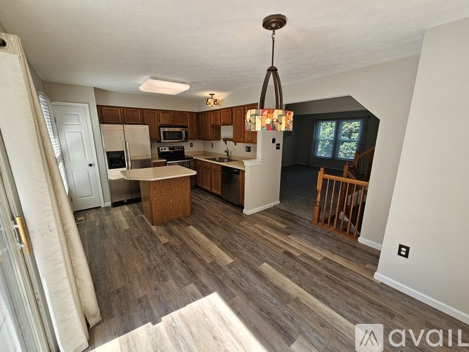 A kitchen with a wooden floor and a chandelier hanging from the ceiling.