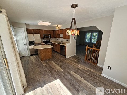 A kitchen with a wooden floor and a chandelier hanging from the ceiling.