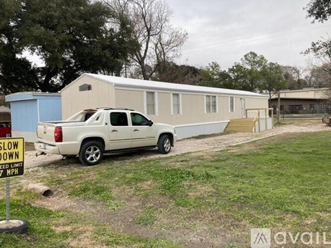 A white pickup truck is parked in front of a mobile home with a "SLOW DOWN" sign in the foreground.