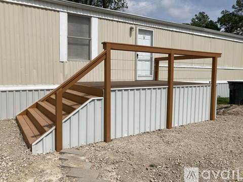 A wooden staircase with a railing is in front of a building.