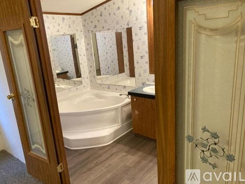 A bathroom with a white bathtub and wooden floors.
