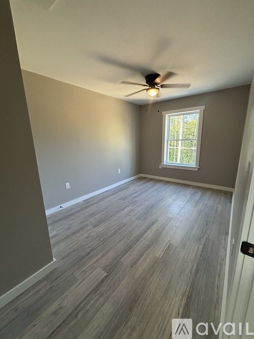 A room with a ceiling fan and a window.