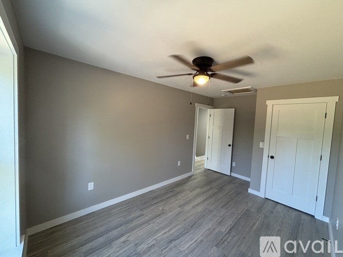 A room with a ceiling fan and wooden flooring.