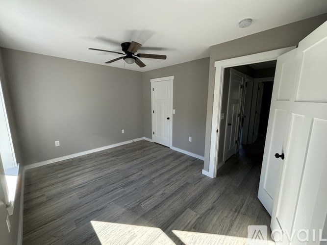 A room with a ceiling fan and wooden flooring.