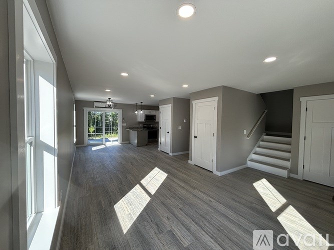 A spacious room with wooden flooring and a staircase leading to another level.