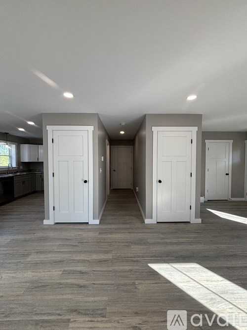 A room with a grey floor and white walls has two white doors.