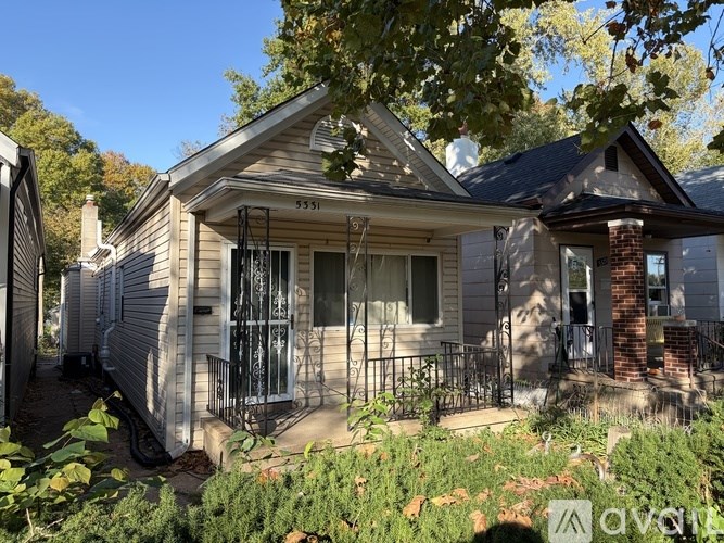 House number 5551 with a front porch and a tree in front.