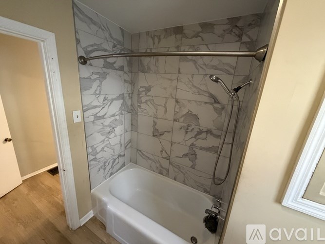 A bathroom with a marble tile shower and a white bathtub.