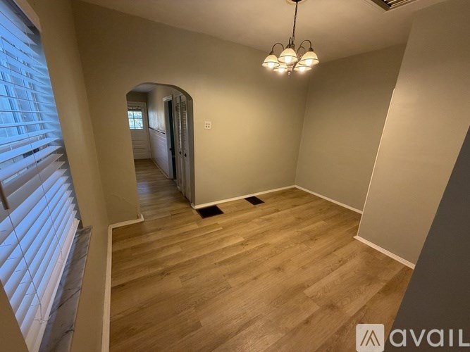 A room with wooden flooring and a chandelier hanging from the ceiling.