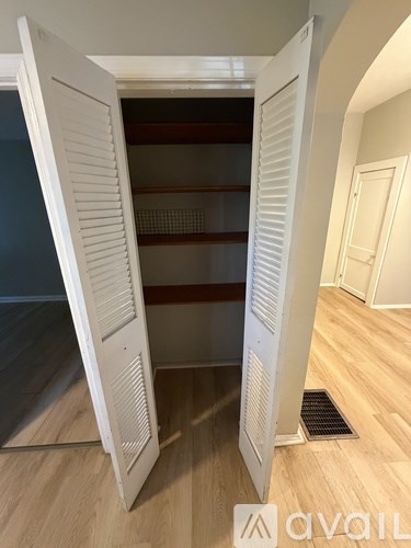 A white open pantry door with shelves inside.