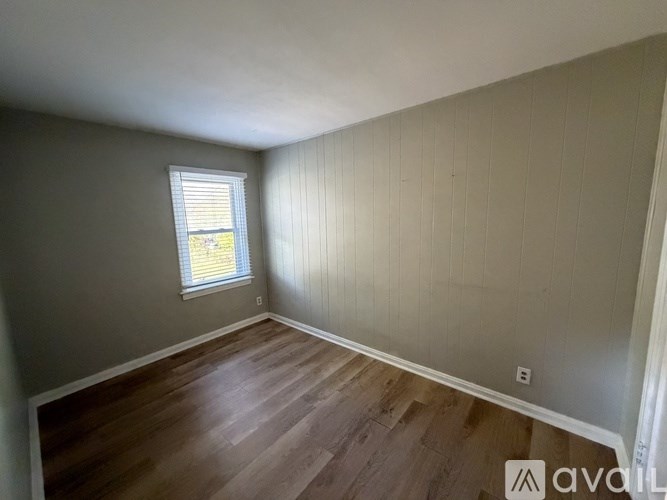 A room with wooden flooring and a window with blinds.