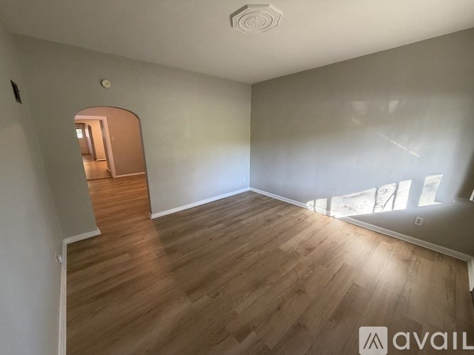 A room with wooden flooring and a doorway leading to another room.