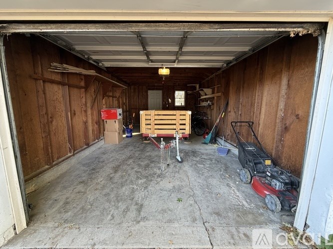A garage with a wooden pallet and a red lawn mower.