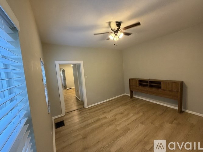 A room with a ceiling fan and wooden flooring.