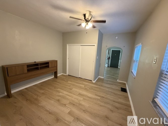 A room with a ceiling fan and wooden flooring.