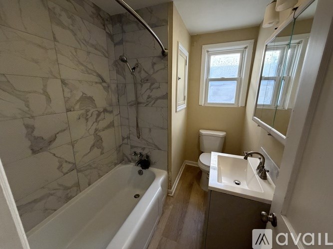 A bathroom with a marble tile shower and a white bathtub.