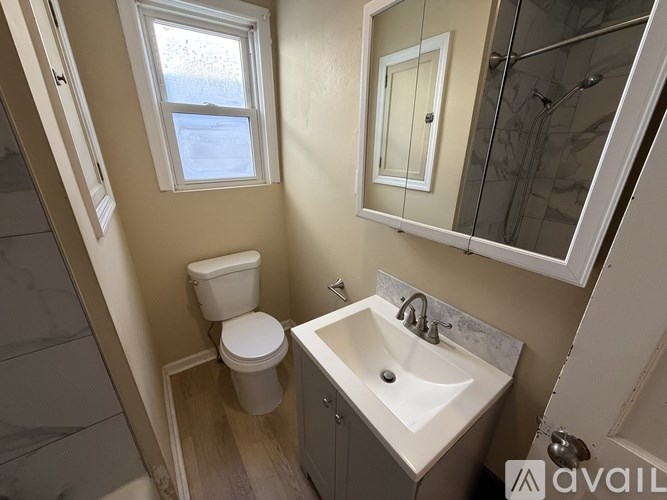 A bathroom with a toilet, sink, and mirror.