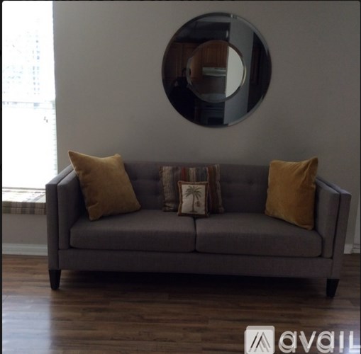 A grey couch with a round mirror and pillows on it.