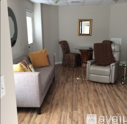 A living room with a grey couch, a brown chair, and a round mirror on the wall.