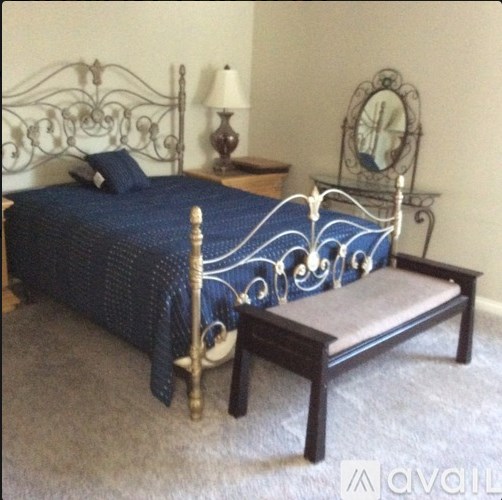 A bed with a blue comforter and a wooden bench in front of it.
