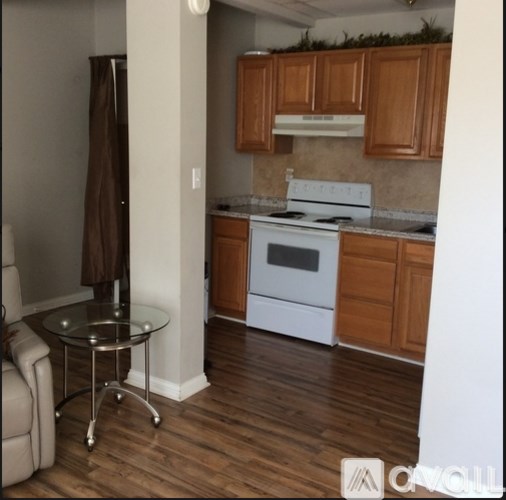 A kitchen with a white stove top oven and wooden cabinets.
