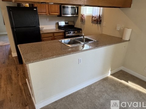 A kitchen with a black fridge, microwave, and stove top oven.