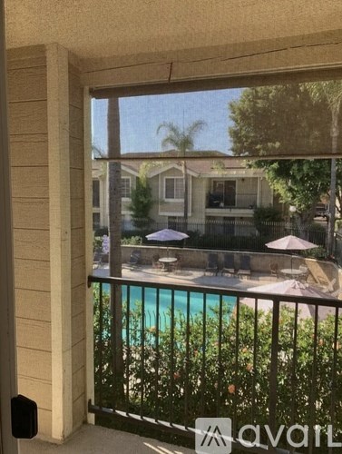 A balcony with a pool and a house in the background.
