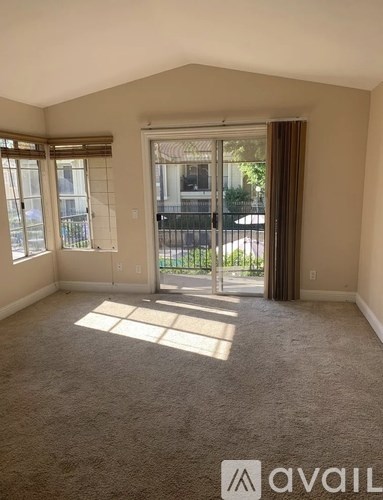 A carpeted room with a sliding glass door leading to a balcony.