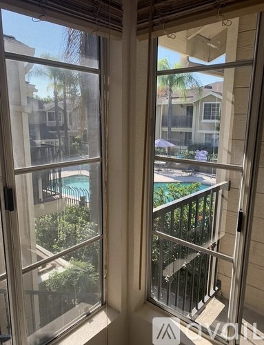 A view from a window looking out at a pool and balcony.