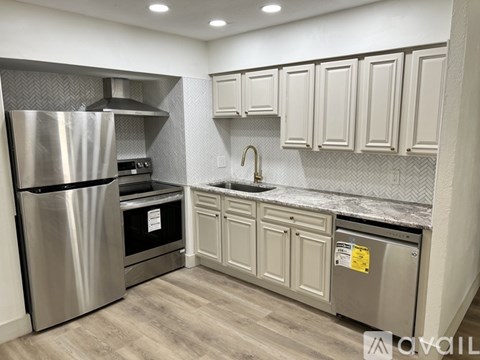 A kitchen with a stainless steel refrigerator and cabinets.
