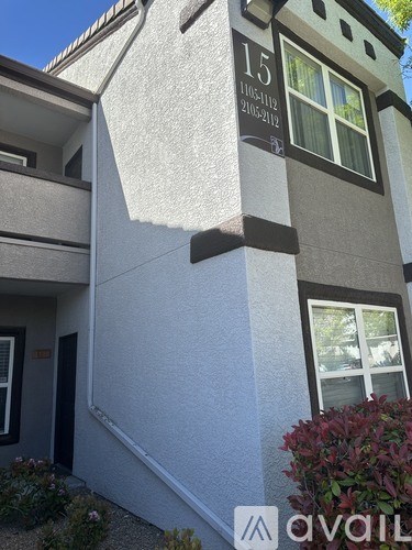 A modern building with a grey and white exterior and a window with a view of a tree.
