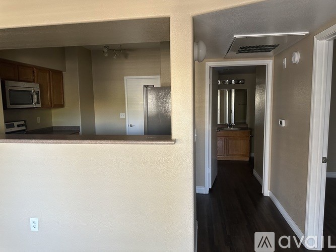 A kitchen with a refrigerator and a hallway with a door.