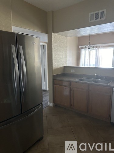 A kitchen with a stainless steel refrigerator and wooden cabinets.