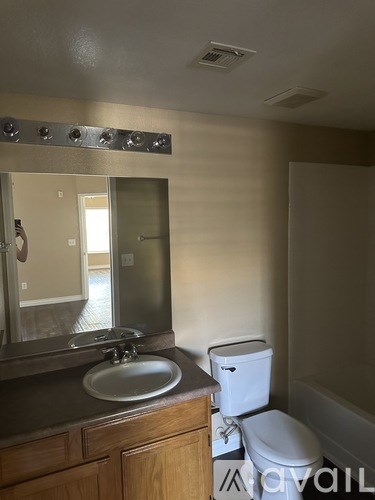 A bathroom with a toilet, sink, and mirror.