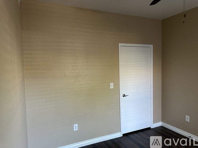 A room with a white door and a fan on the ceiling.