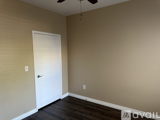 A room with a white door and a ceiling fan.
