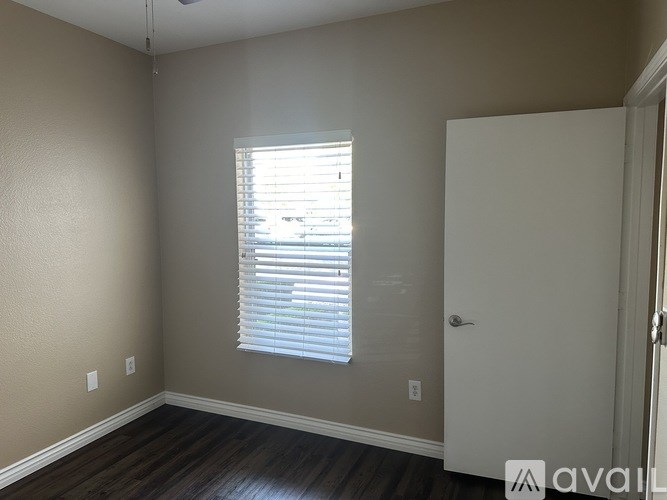 A room with a window covered by blinds and a white door.
