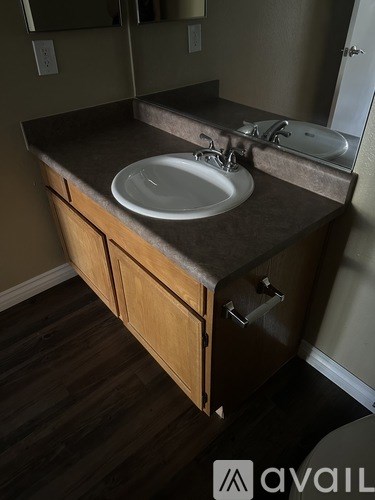 A bathroom sink with a countertop and wooden cabinets.