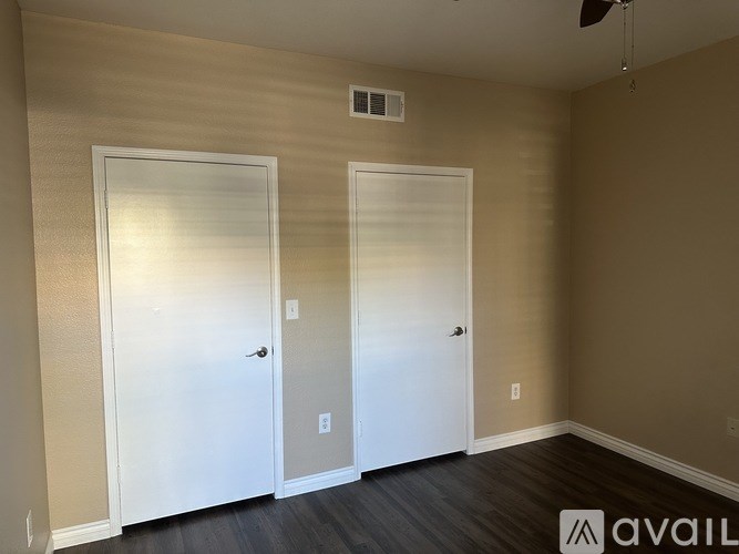 Two white doors in a room with beige walls and a ceiling fan.