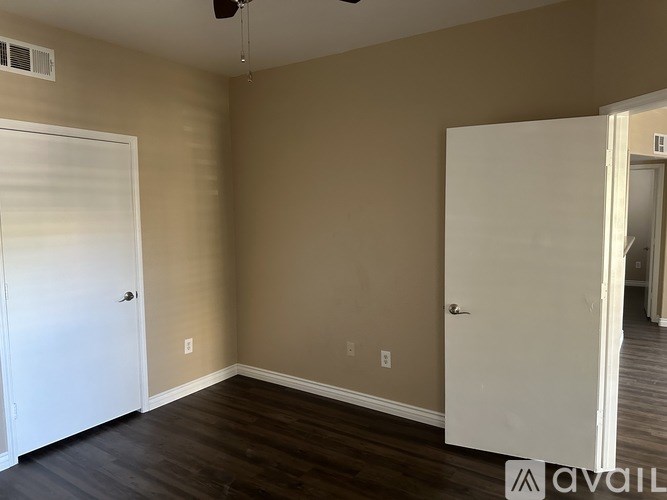 A room with a white door and a ceiling fan.