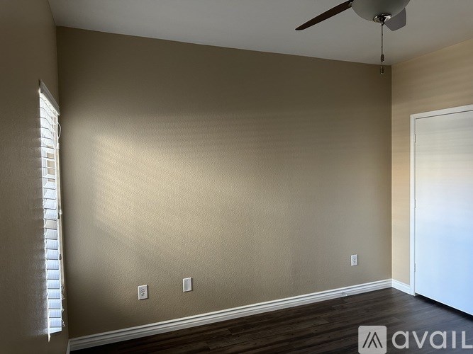 A room with a ceiling fan and a window with blinds.